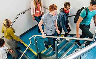 Group of students and teachers walking up a blue staircase