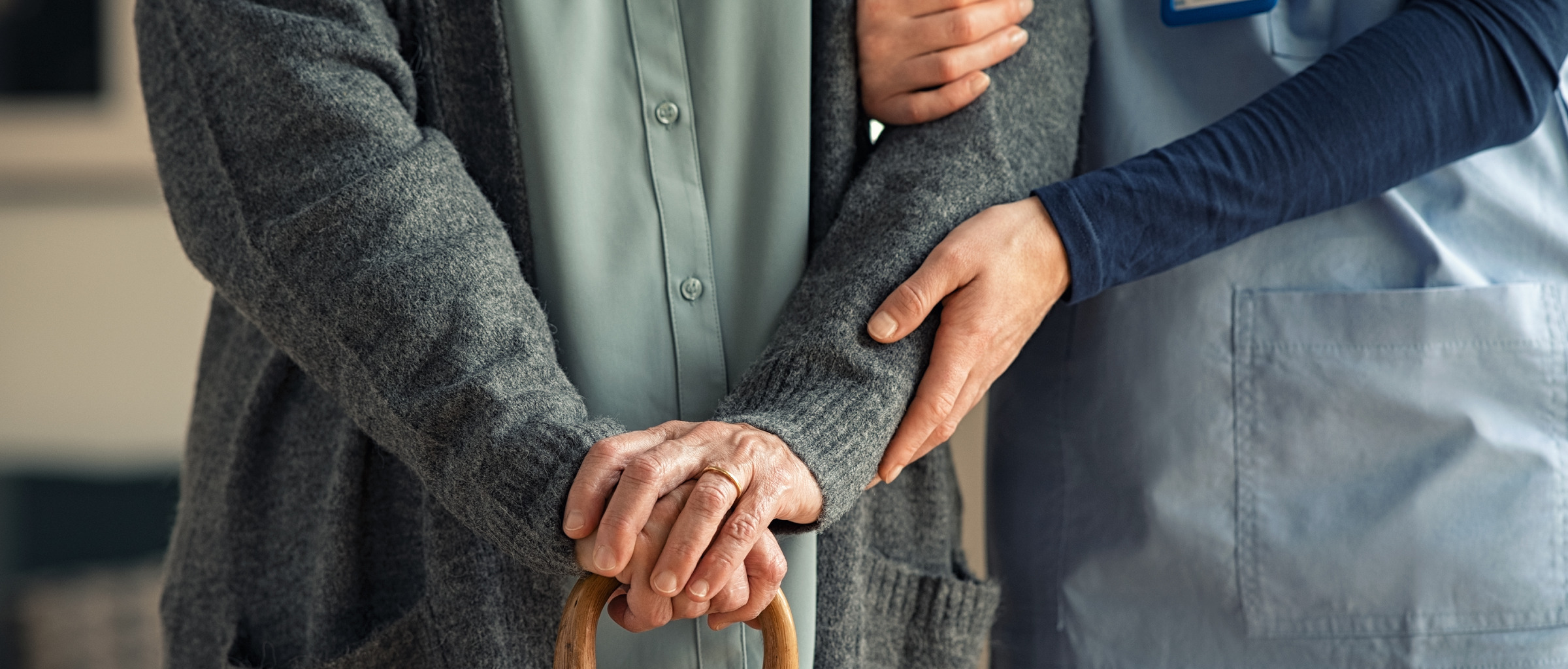 Nurse and person with a cane walking together.